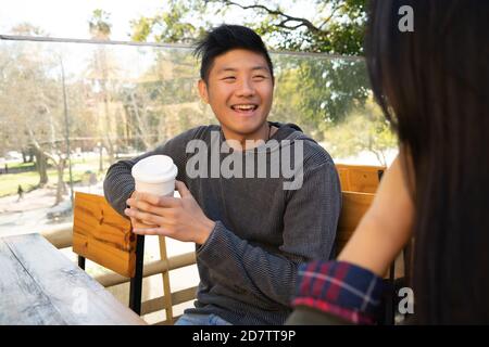 Portrait of lovely asian couple having good time and talking to each other in coffee shop. Stock Photo