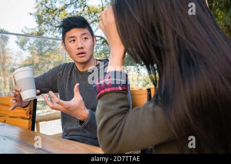 Portrait of lovely asian couple having good time and talking to each other in coffee shop. Stock Photo