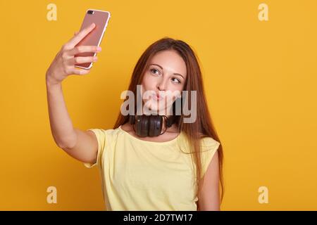 Close up portrait of beautiful amazing lady making selfie via telephone, taking photo for her boyfriend, wearing casual t shirt, having long hair, pos Stock Photo
