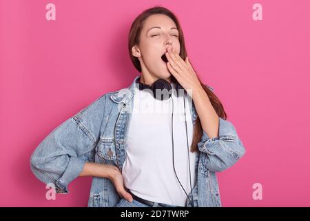 Shot of sleepy attractive caucasian woman with long hair, wearing casual outfit, feels tired after night without sleep, yawning with closed eyes, cove Stock Photo