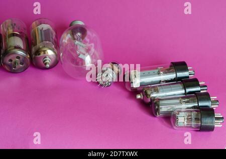 Various vacuum tubes on a pink background. A group of random radio tubes. Types of obsolete electrical parts. Selective focus. Stock Photo