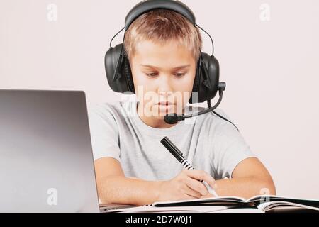 Boy in a headphones doing homework with notebook computer. Online learning, remote education at home Stock Photo