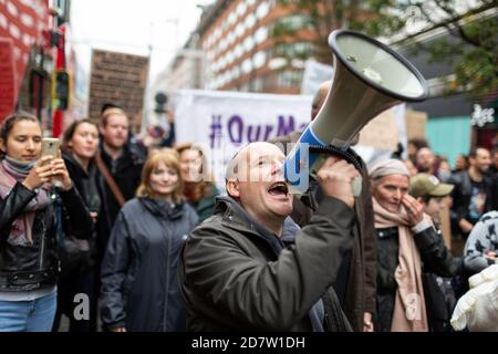 A protester speaks into a megaphone amongst a crowd during an anti-lockdown rally in London, 24 October 2020 Stock Photo