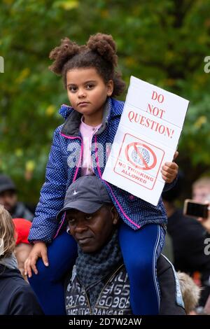 A child with protest placard rides piggyback during an anti-lockdown rally in London, 24 October 2020 Stock Photo