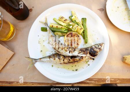 Mackerel fried with courgette and lemon, taverna at Athens Metaxourgeio  Greece Stock Photo