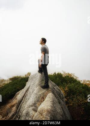 Epic adventure of brave and ambitious hiker trekking activity on wild cliff, pose with panoramic nature mountain landscape. Winner motivation and Stock Photo