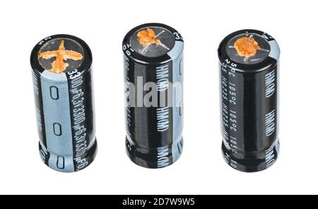 Bad swollen aluminum electrolytic capacitors with grooves on metal top for bursting at overpressure and leaked electrolyte. High ESR. Electronic waste. Stock Photo