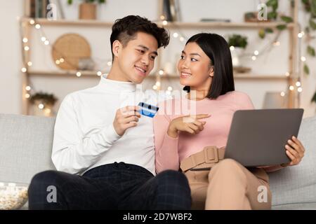 Asian Couple Shopping Via Laptop And Credit Card At Home Stock Photo