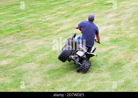 The back of a adult stunting on a childs quad Stock Photo