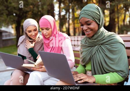 Three Modern Arab Women Learning With Laptop And Books Outside Stock Photo