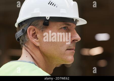 Side view portrait of professional construction worker wearing helmet and looking away, copy space Stock Photo
