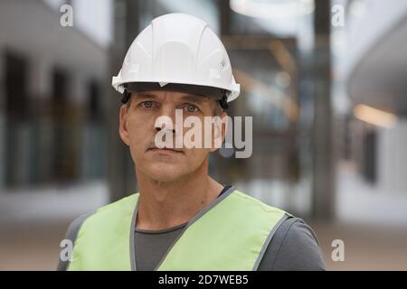 Close up portrait of professional construction worker looking at camera while standing on construction site, copy space Stock Photo