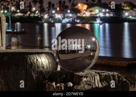 Ventura Marina waters reflecting harbor lamps in the ocean water surface while looking through spherical round lens ball. Stock Photo