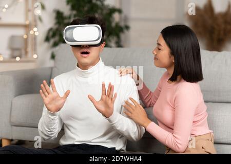 Millennial Couple Using Virtual Reality Glasses Playing Game At Home Stock Photo