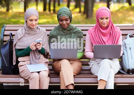 Arab Ladies Using Smartphone And Computers Learning Online In Park Stock Photo