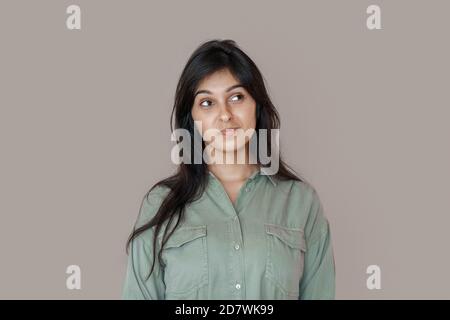 Doubtful young indian woman looking at copy space, dreaming or choosing.