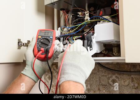 The worker's hands checks the serviceability of the electronics of the gas boiler. Stock Photo