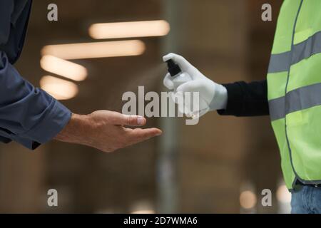 Side view close up of supervisor sanitizing hands of workers with spray , corona virus safety Stock Photo