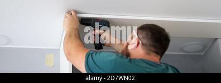 A man collects furniture at home using screwdriver Stock Photo