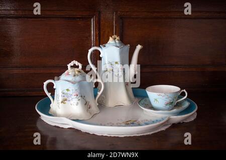 An antique porcelain service - a teapot, two cups and saucers in blue and white with flowers - stands on the chest of drawers. Stock Photo