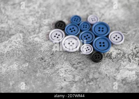 Pile of blue matte buttons on concrete background, macro bokeh. beautiful needlework. Use for sew. Space for text Stock Photo