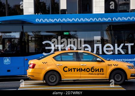 Moscow, Russia. 25th of October, 2020 Yellow taxi with the word 'Citymobil' on the car door on the background of an electric bus in the center of Moscow, Russia Stock Photo