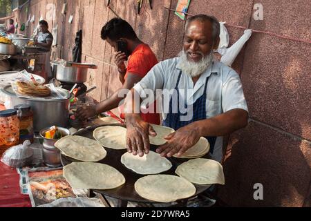 A smiling street vendor cooks chapatis at his food stall in the old city of Delhi Stock Photo