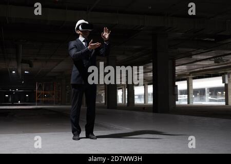 Dramatic full length portrait of businessman wearing VR gear at construction site while visualizing future project in 3D, copy space Stock Photo