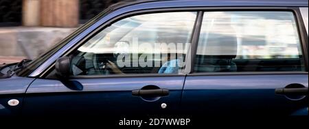 Belgrade, Serbia - October 02, 2020: Woman driving a car on city street, alone, through window with reflections and blurs Stock Photo