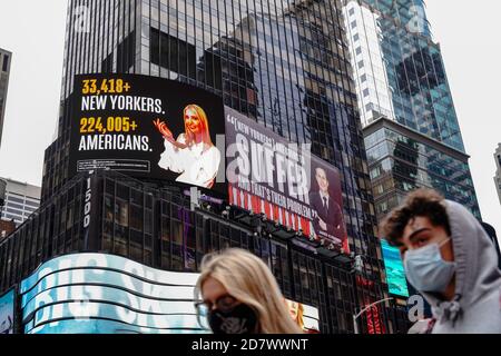 A woman wearing a face mask walks past a Lincoln Project Billboard that depicts Ivanka trump presenting the number of New Yorkers and americans who have died of Covid-19 and Jared Kushner next to a Vanity Fair quote. Stock Photo