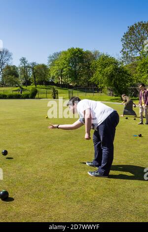 Young man having a first go at 'have a go at crown green bowling' on the bowling green at Farnworth central park, Greater Manchester. Stock Photo