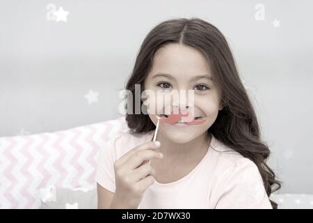 Having fun with face mustache. Happy small girl. Small girl hold fake mustache on face. Happy childhood. My childhood is amazing. Stock Photo