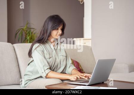 Young indian woman using laptop computer working at home office. Stock Photo