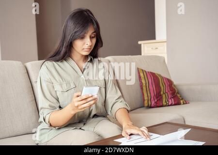 Indian woman using mobile e-bank app paying bills online on smartphone. Stock Photo