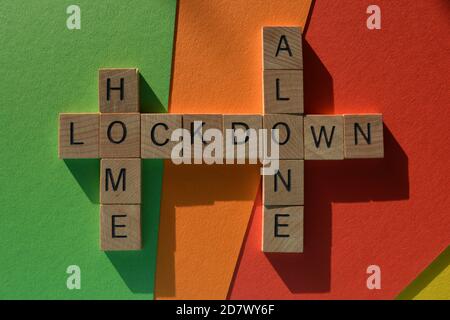 Home, Alone, Lockdown, words in wood alphabet letters in crossword form on colorful background Stock Photo