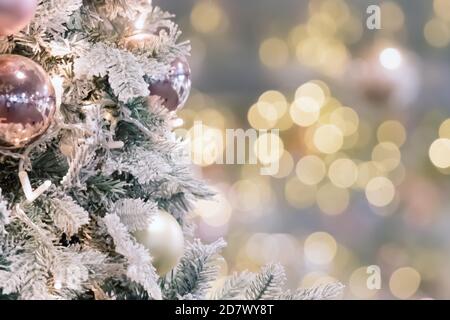Decorated artificial christmas tree on soft blurred golden lights. Baubles on tree branch. Stock Photo