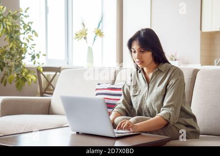 Young indian woman using laptop computer working at home office. Stock Photo