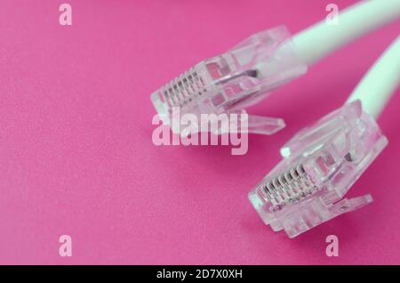 White cord with connector rj45 on a bright pink background. network ethernet cable plugs Stock Photo
