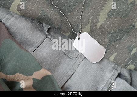 Silvery military beads with dog tag on different camouflage fatigue uniforms. Army token on soldiers camo jackets Stock Photo