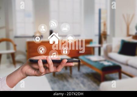 Smart home technology virtual digital screening on smartphone app home controlling lights,lock,cctv home interior, person holding device Stock Photo