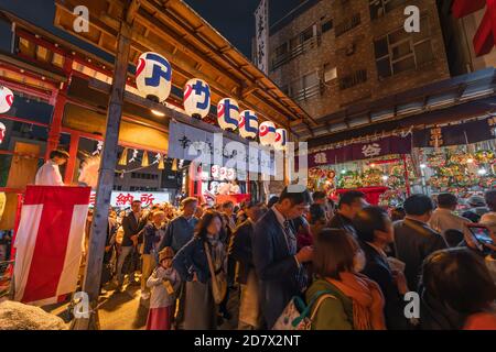 asakusa, japan - november 08 2019: Crowd at the gate of Ootori shrine ornate with paper lanterns and surrounded by Negi boys blessing the faithful to Stock Photo