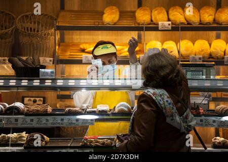 BELGRADE, SERBIA - OCTOBER 14, 2020: Female staff, Bakter, serving clients and holding cash banknotes in a bakery wearing a respiratory face mask in B Stock Photo