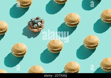 Colorful french cookies macarons pattern on pastel blue background. Minimal concept. Chocolate dessert, macaroon on colored surface. Daylight, natural Stock Photo
