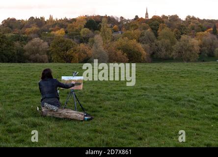 London, Britain. 25th Oct, 2020. A woman paints on the grass in Hampstead Heath, north London, Britain, on Oct. 25, 2020. Another 19,790 people in Britain have tested positive for COVID-19, bringing the total number of coronavirus cases in the country to 873,800, according to official figures released Sunday. The coronavirus-related deaths in Britain rose by 151 to 44,896, the data showed. Credit: Han Yan/Xinhua/Alamy Live News Stock Photo