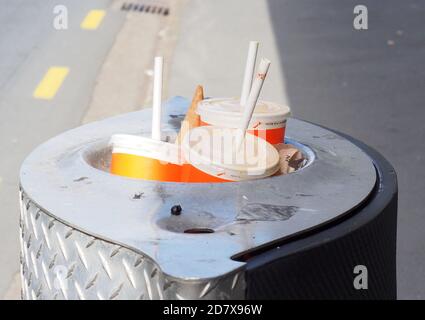 Single use plastic drink containers with straws, dumped in a full city bin Stock Photo