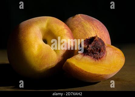Peaches on a wooden table with moody ambient light, black background, a chiaroscuro, baroque style photography. Stock Photo