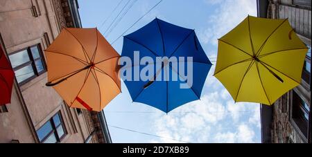 Umbrellas hanging in the air above the street decorating the city. Stock Photo