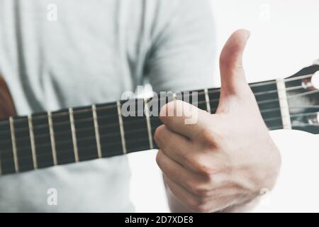 Close-up of man showing thumbs up on guitar fretboard because something good has happened. Music education concept. Stock Photo