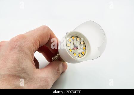Man holds in his hand a broken led lamp on a white background Stock Photo
