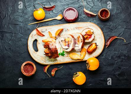 Baked pork roll with autumn persimmon.Meat stuffed with fruits.Autumn food Stock Photo
